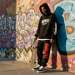 Outfit elegante con felpa Trapstar mostrato in una scena urbana.
